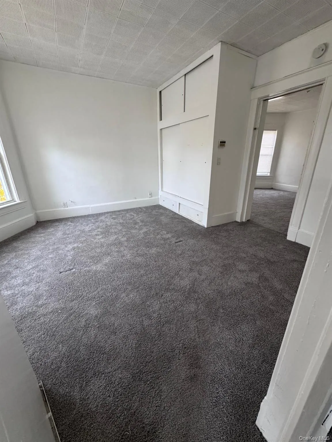 Unfurnished bedroom featuring dark colored carpet and baseboards Unfurnished bedroom featuring dark colored carpet and baseboards