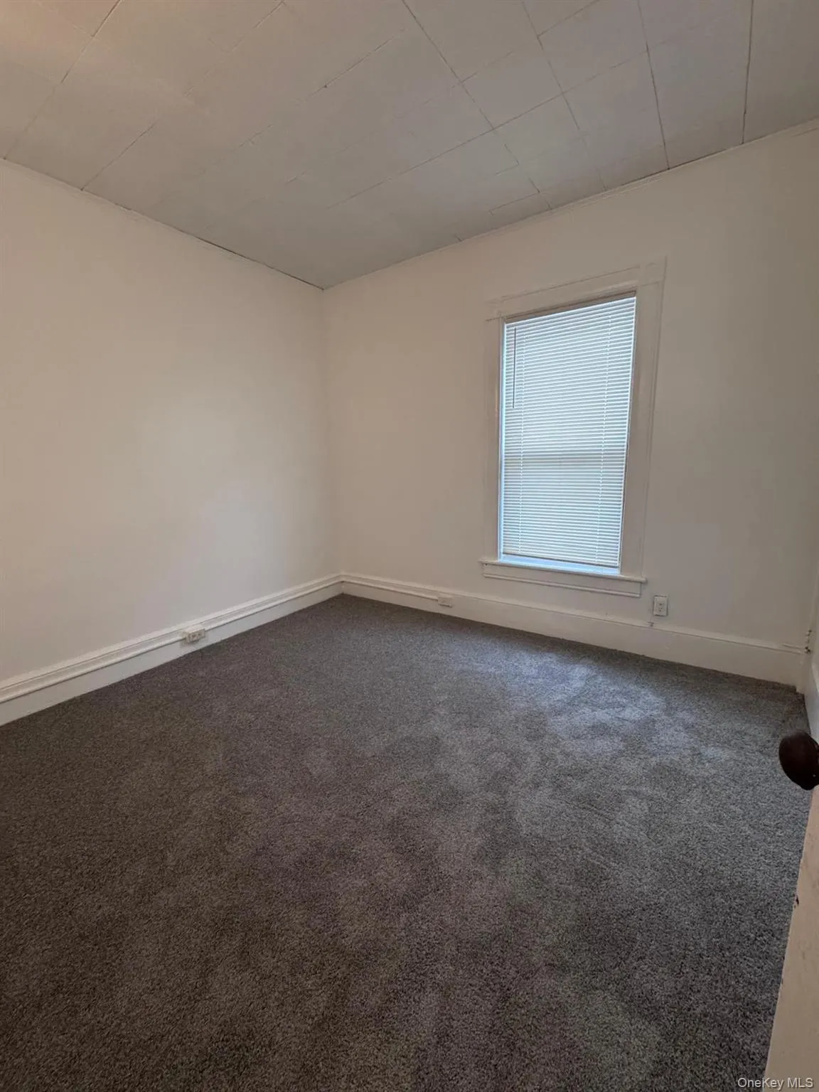 Unfurnished room with dark carpet and baseboards Unfurnished room with dark carpet and baseboards