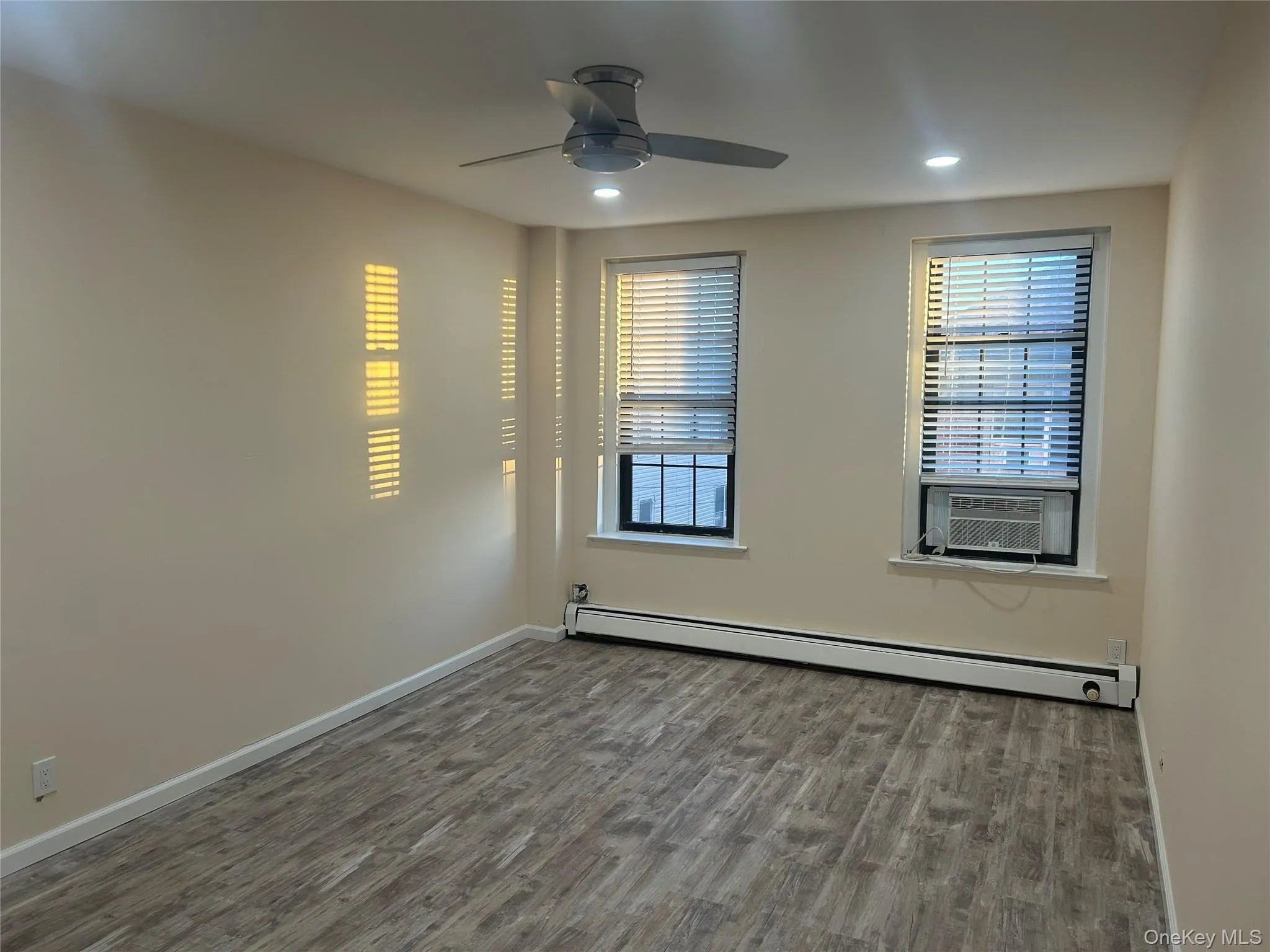 Unfurnished room with dark wood finished floors, baseboard heating, recessed lighting, ceiling fan, and cooling unit Unfurnished room with dark wood finished floors, baseboard heating, recessed lighting, ceiling fan, and cooling unit