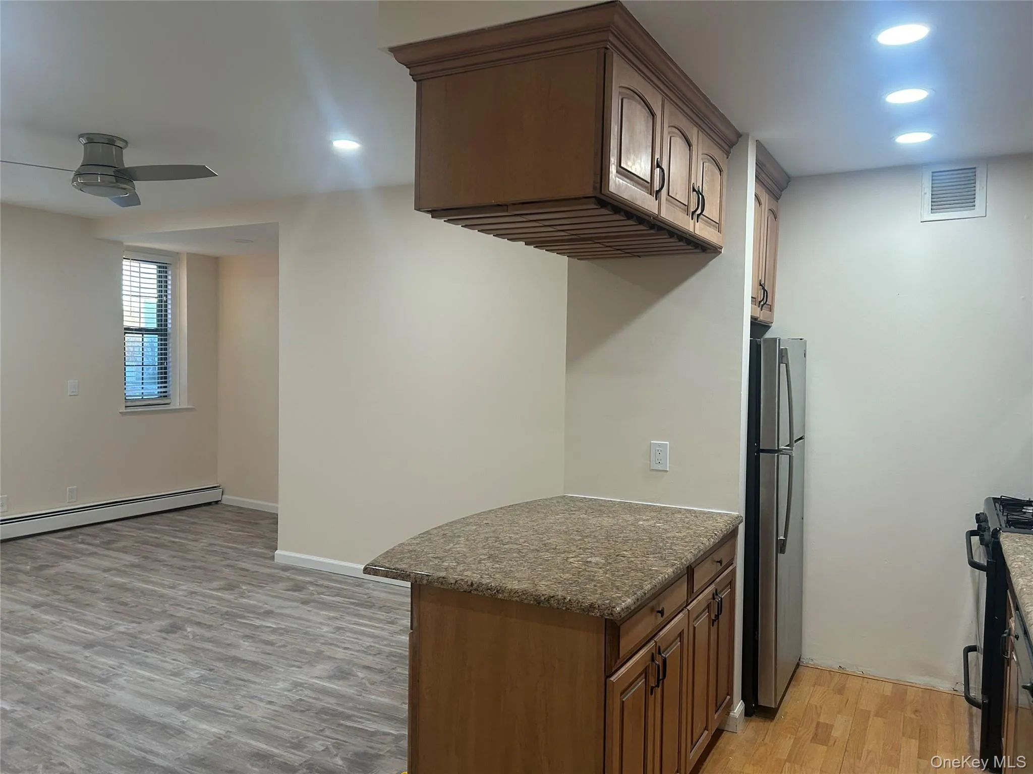 Kitchen featuring recessed lighting, dark stone countertops, light wood-style flooring, freestanding refrigerator, and black gas stove Kitchen featuring recessed lighting, dark stone countertops, light wood-style flooring, freestanding refrigerator, and black gas stove