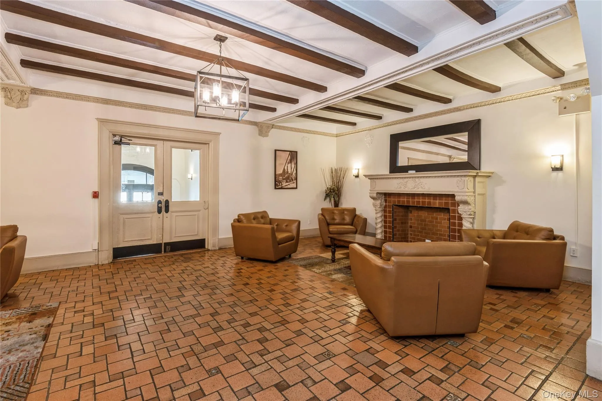 Living area with a fireplace, french doors, beamed ceiling, brick patterned flooring, and a chandelier Living area with a fireplace, french doors, beamed ceiling, brick patterned flooring, and a chandelier
