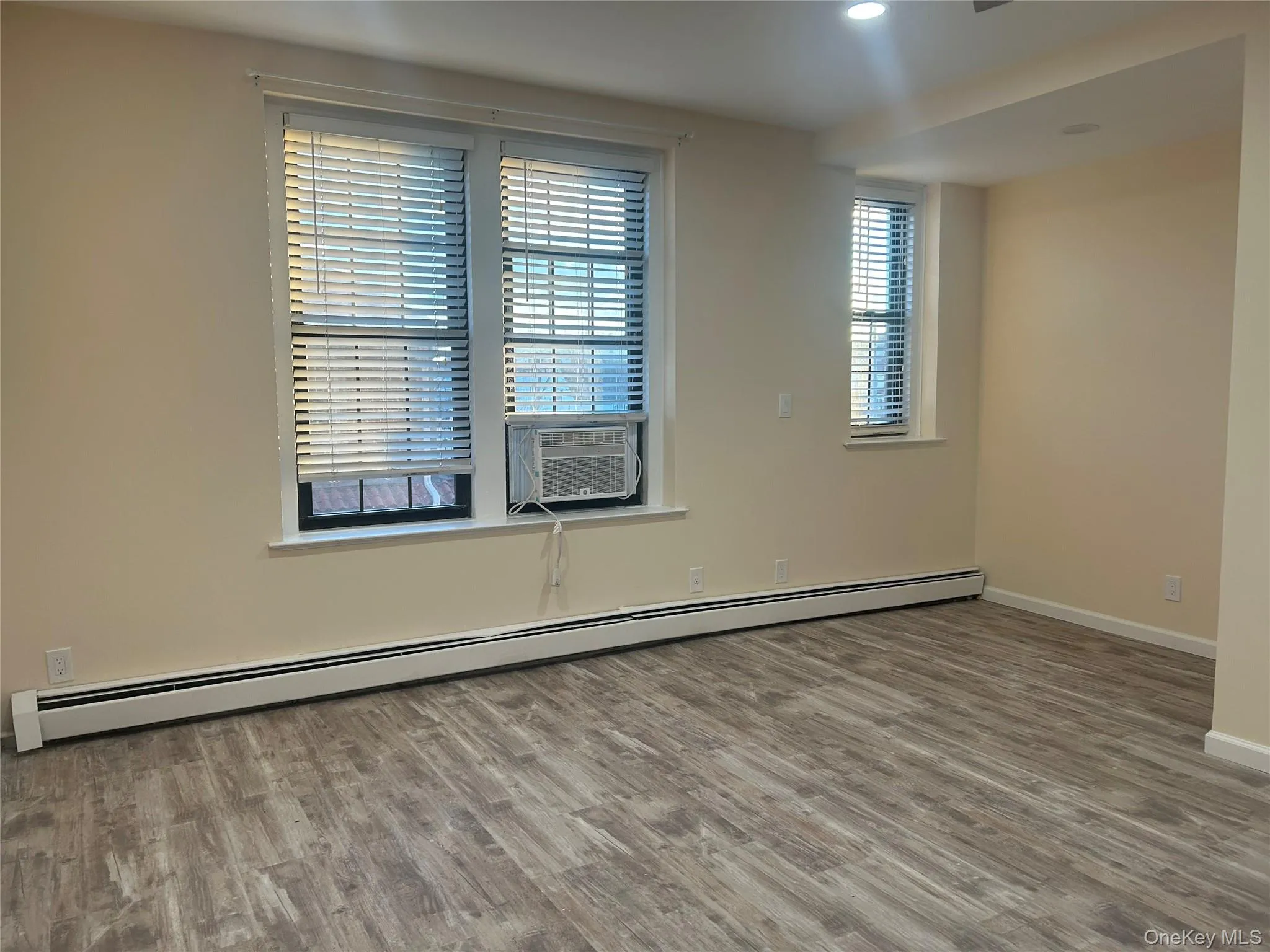 Spare room featuring a baseboard heating unit, wood finished floors, cooling unit, and recessed lighting Spare room featuring a baseboard heating unit, wood finished floors, cooling unit, and recessed lighting