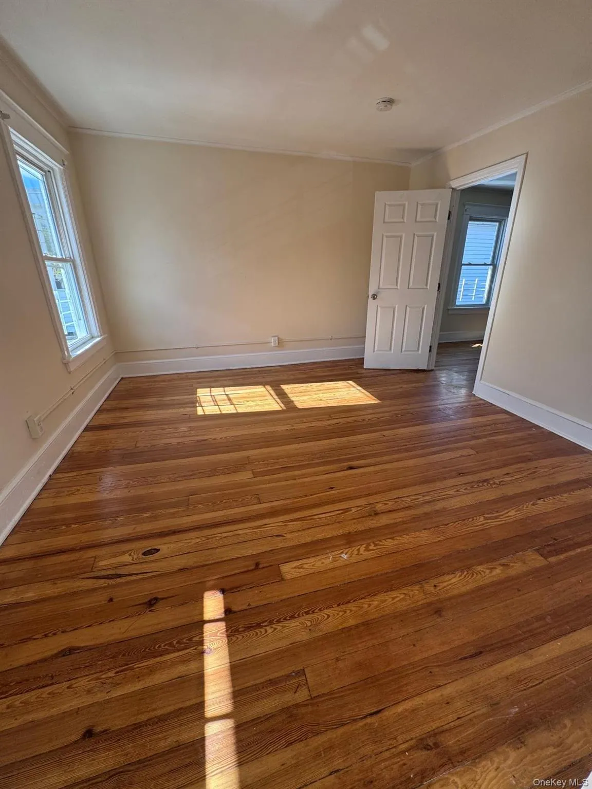 Unfurnished room featuring dark wood finished floors, plenty of natural light, and ornamental molding Unfurnished room featuring dark wood finished floors, plenty of natural light, and ornamental molding