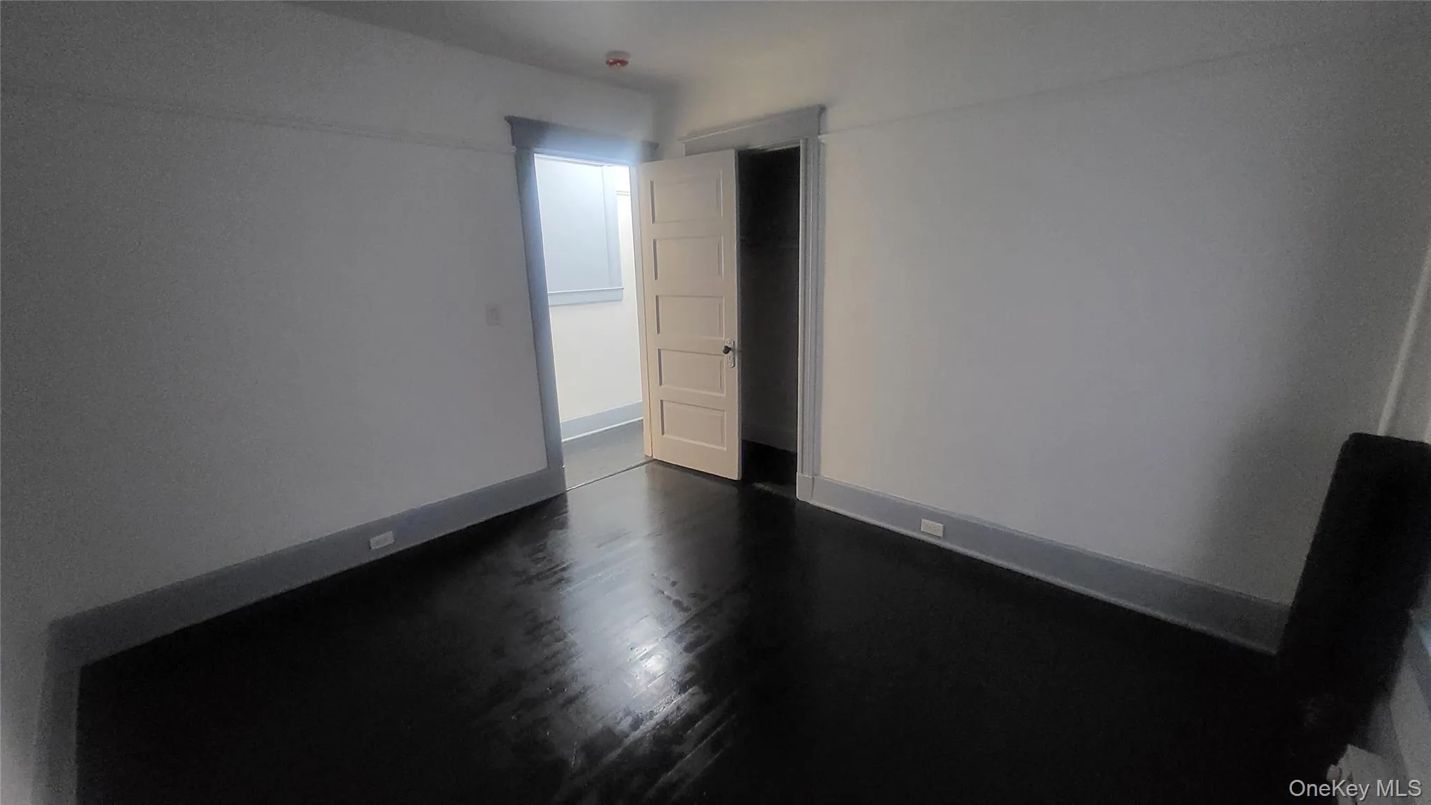 Spare room featuring baseboards and dark wood-style flooring Spare room featuring baseboards and dark wood-style flooring