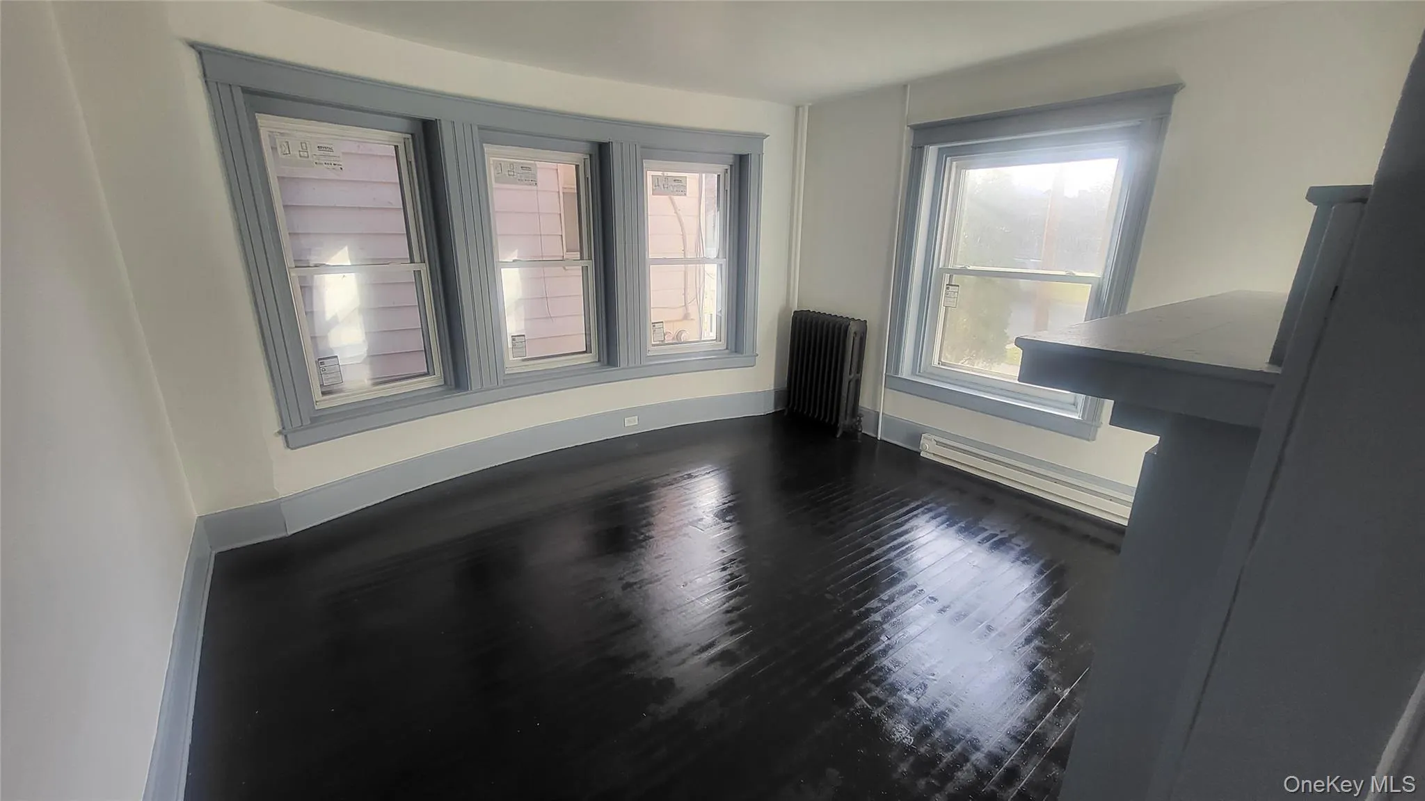 Unfurnished room with radiator, dark wood finished floors, and a baseboard heating unit Unfurnished room with radiator, dark wood finished floors, and a baseboard heating unit