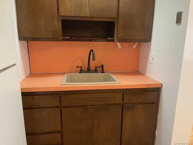 Kitchen featuring freestanding refrigerator, light countertops, and dark brown cabinets Kitchen featuring freestanding refrigerator, light countertops, and dark brown cabinets