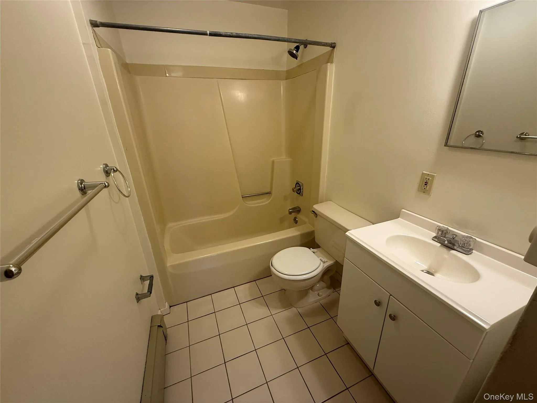 Full bath featuring vanity, bathtub / shower combination, light tile patterned floors, and a baseboard heating unit Full bath featuring vanity, bathtub / shower combination, light tile patterned floors, and a baseboard heating unit