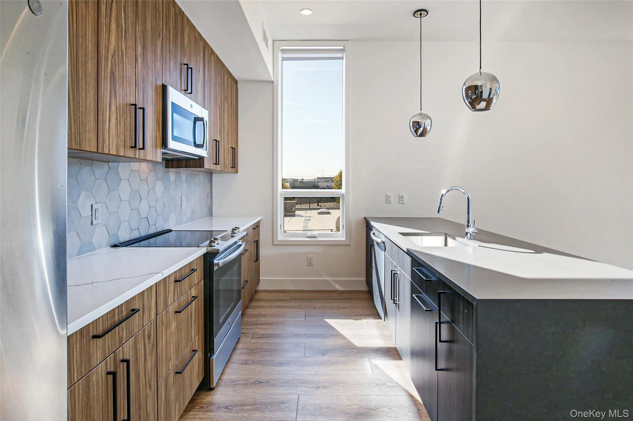 Kitchen featuring pendant lighting, sink, hardwood / wood-style flooring, appliances with stainless steel finishes, and tasteful backsplash Kitchen featuring pendant lighting, sink, hardwood / wood-style flooring, appliances with stainless steel finishes, and tasteful backsplash