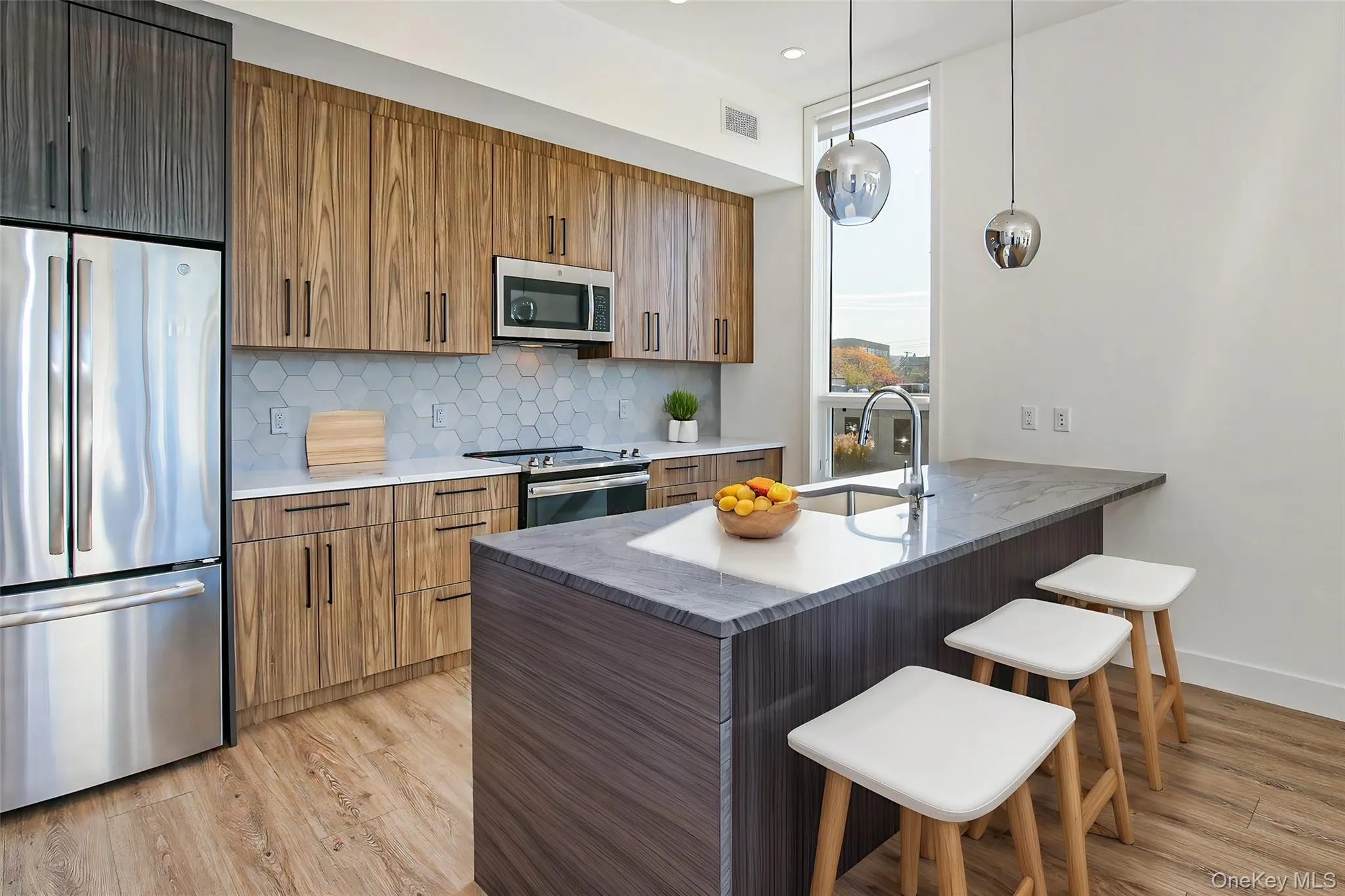 Kitchen with sink, a breakfast bar area, hanging light fixtures, kitchen peninsula, and stainless steel appliances, virtually staged Kitchen with sink, a breakfast bar area, hanging light fixtures, kitchen peninsula, and stainless steel appliances, virtually staged