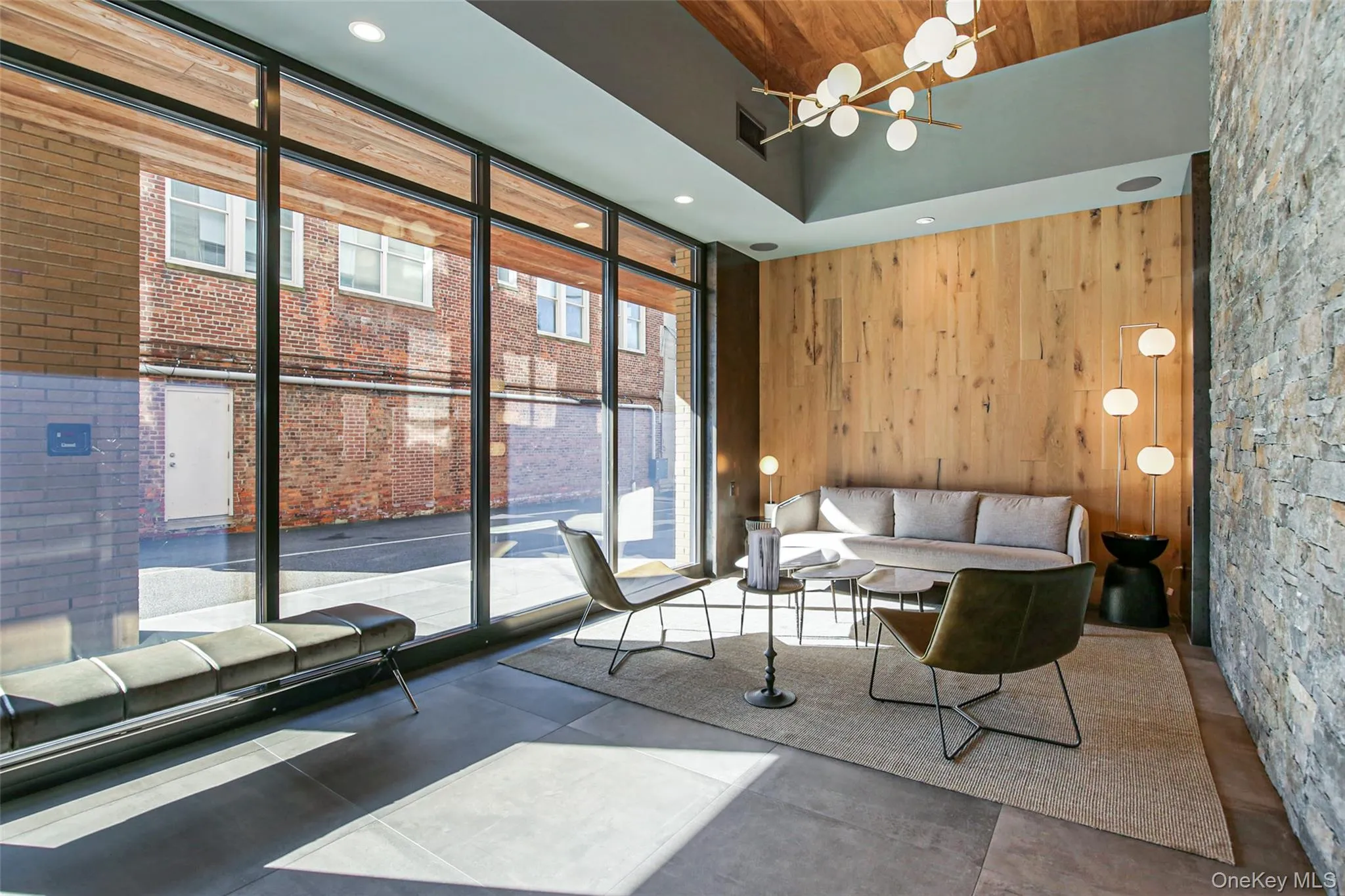 Living room featuring floor to ceiling windows, a high ceiling, and wood walls Living room featuring floor to ceiling windows, a high ceiling, and wood walls