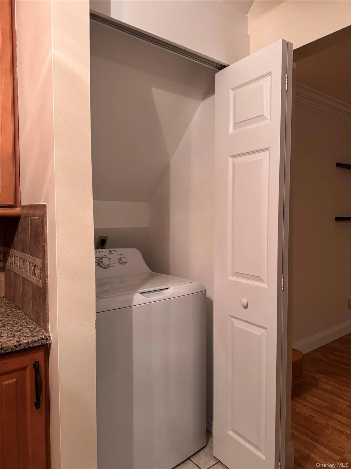 Laundry room featuring washer / dryer, light wood-type flooring, and ornamental molding Laundry room featuring washer / dryer, light wood-type flooring, and ornamental molding