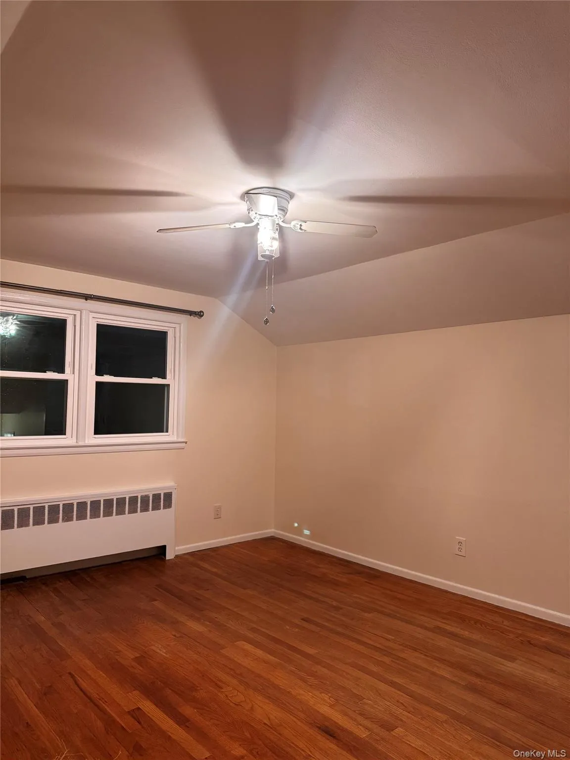 Additional living space featuring radiator heating unit, vaulted ceiling, and dark wood-type flooring Additional living space featuring radiator heating unit, vaulted ceiling, and dark wood-type flooring