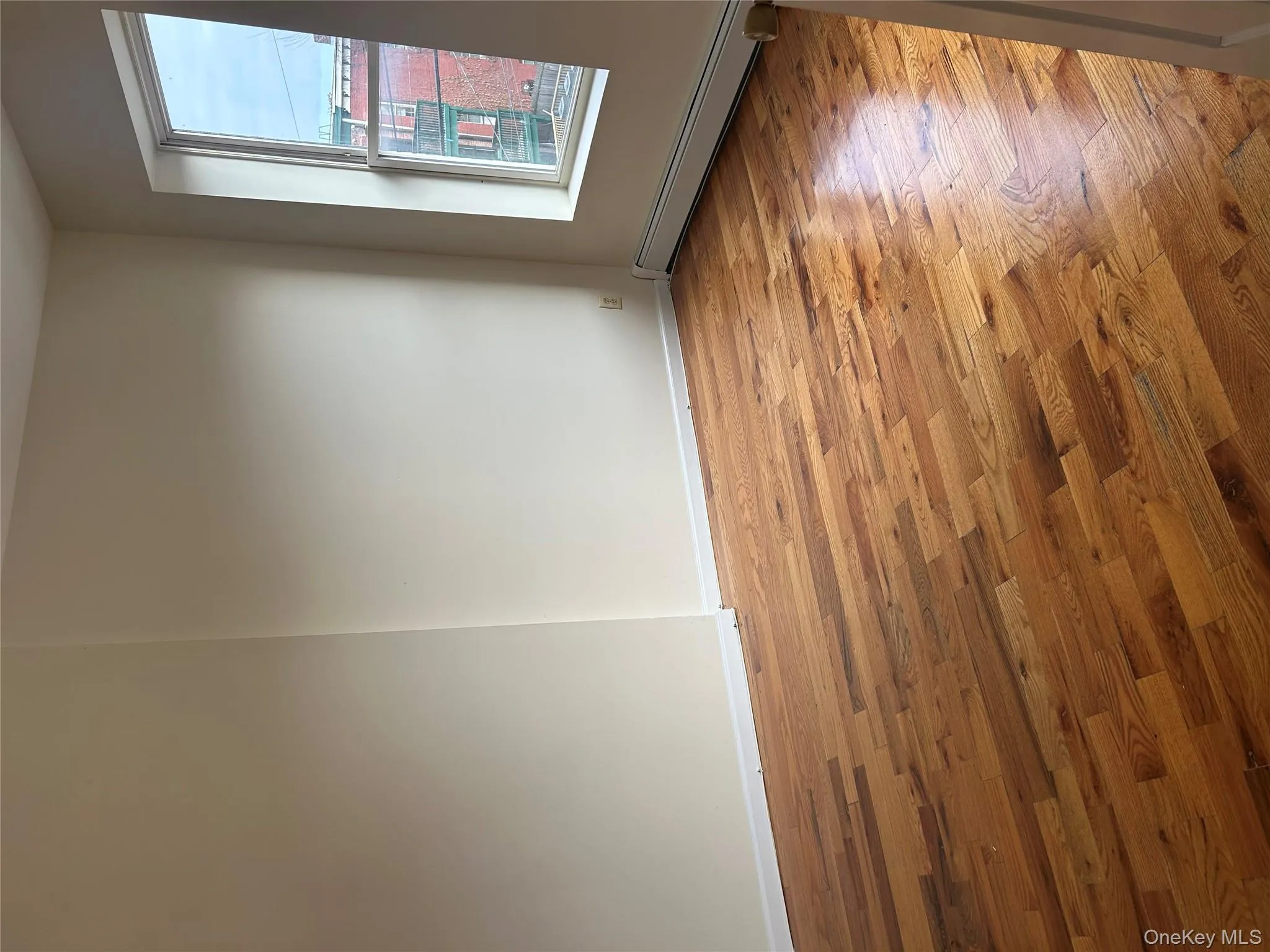 Unfurnished room with light wood finished floors and a baseboard heating unit Unfurnished room with light wood finished floors and a baseboard heating unit