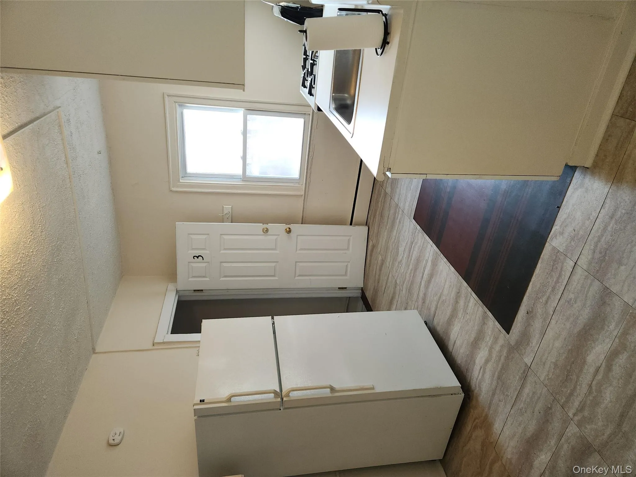 Kitchen featuring refrigerator, a textured ceiling, light countertops, baseboard heating, and stove Kitchen featuring refrigerator, a textured ceiling, light countertops, baseboard heating, and stove