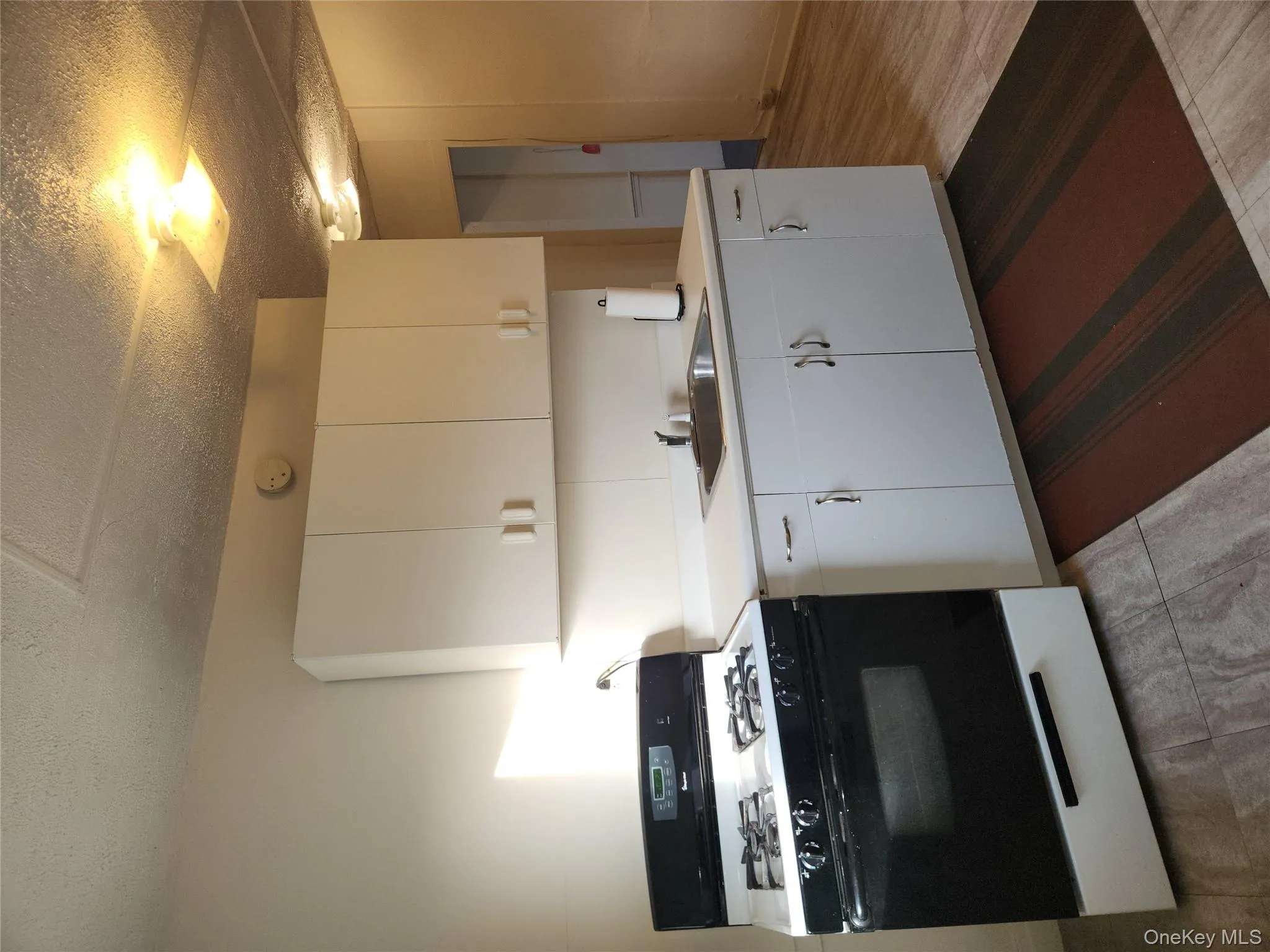 Kitchen featuring range, white cabinets, light countertops, and a textured ceiling Kitchen featuring range, white cabinets, light countertops, and a textured ceiling