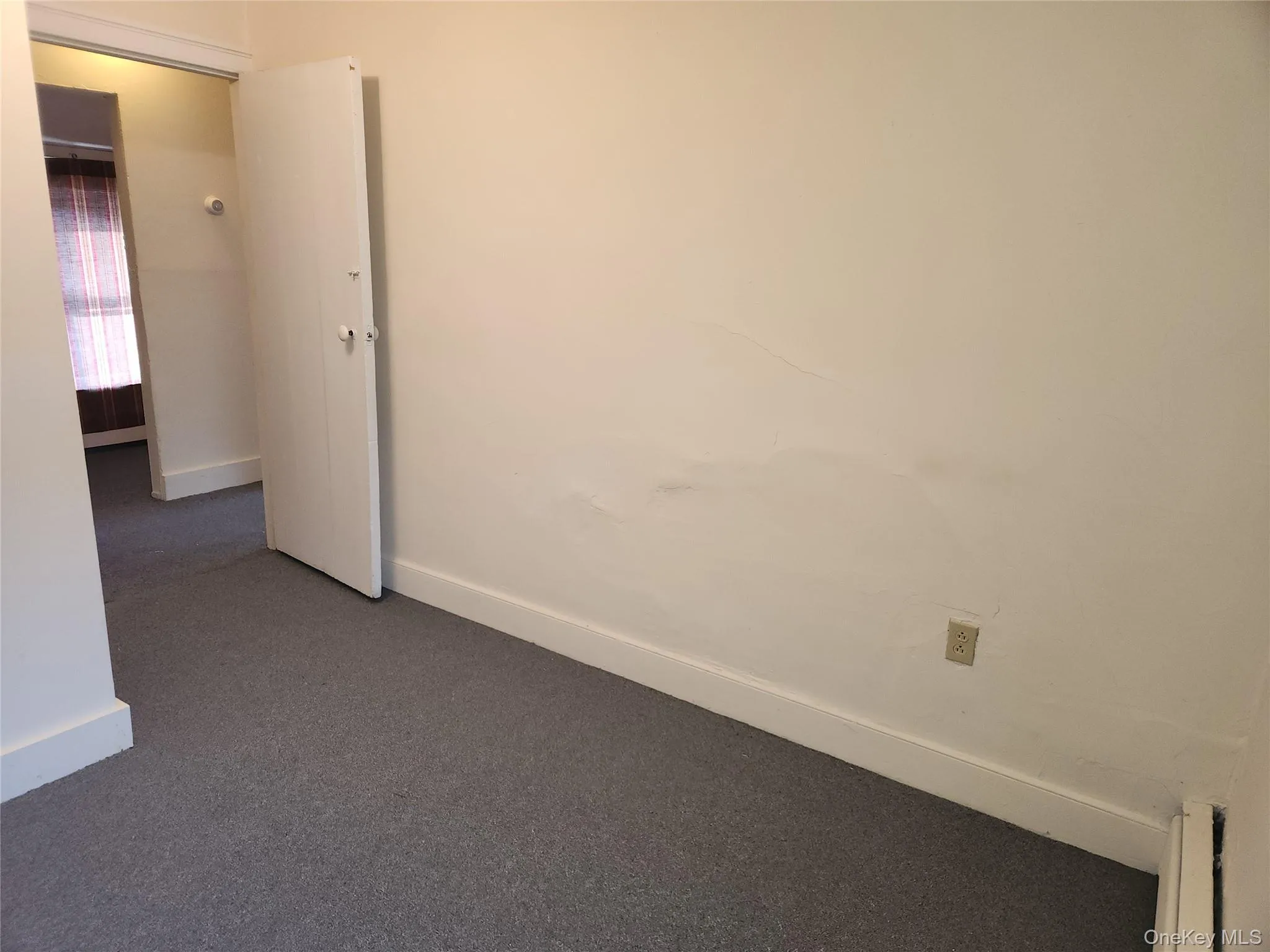 Spare room with baseboards and dark colored carpet Spare room with baseboards and dark colored carpet