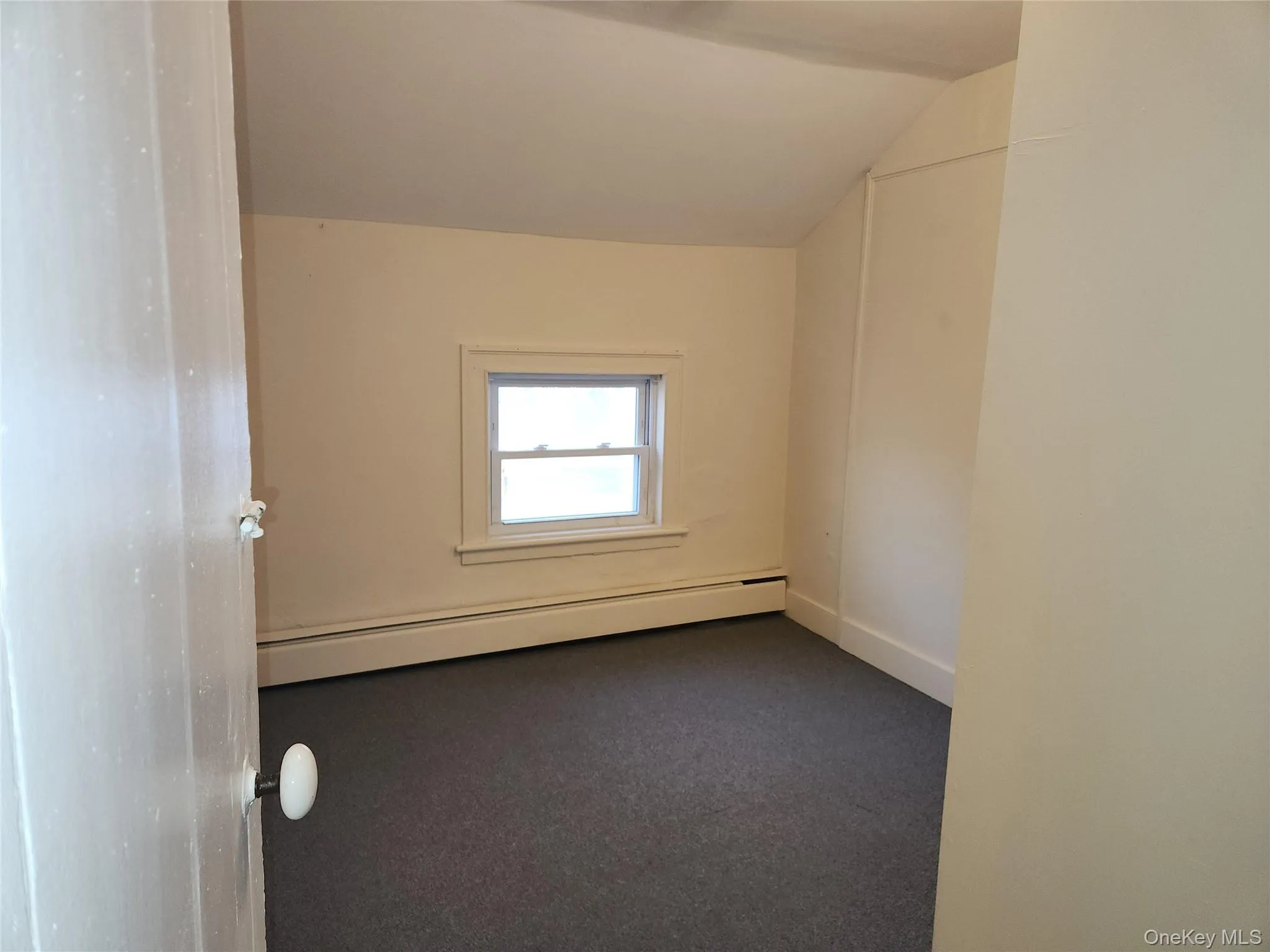 Carpeted empty room featuring a baseboard heating unit and vaulted ceiling Carpeted empty room featuring a baseboard heating unit and vaulted ceiling