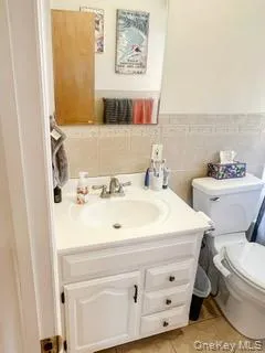 Bathroom featuring vanity, tile walls, wainscoting, and light tile patterned flooring Bathroom featuring vanity, tile walls, wainscoting, and light tile patterned flooring