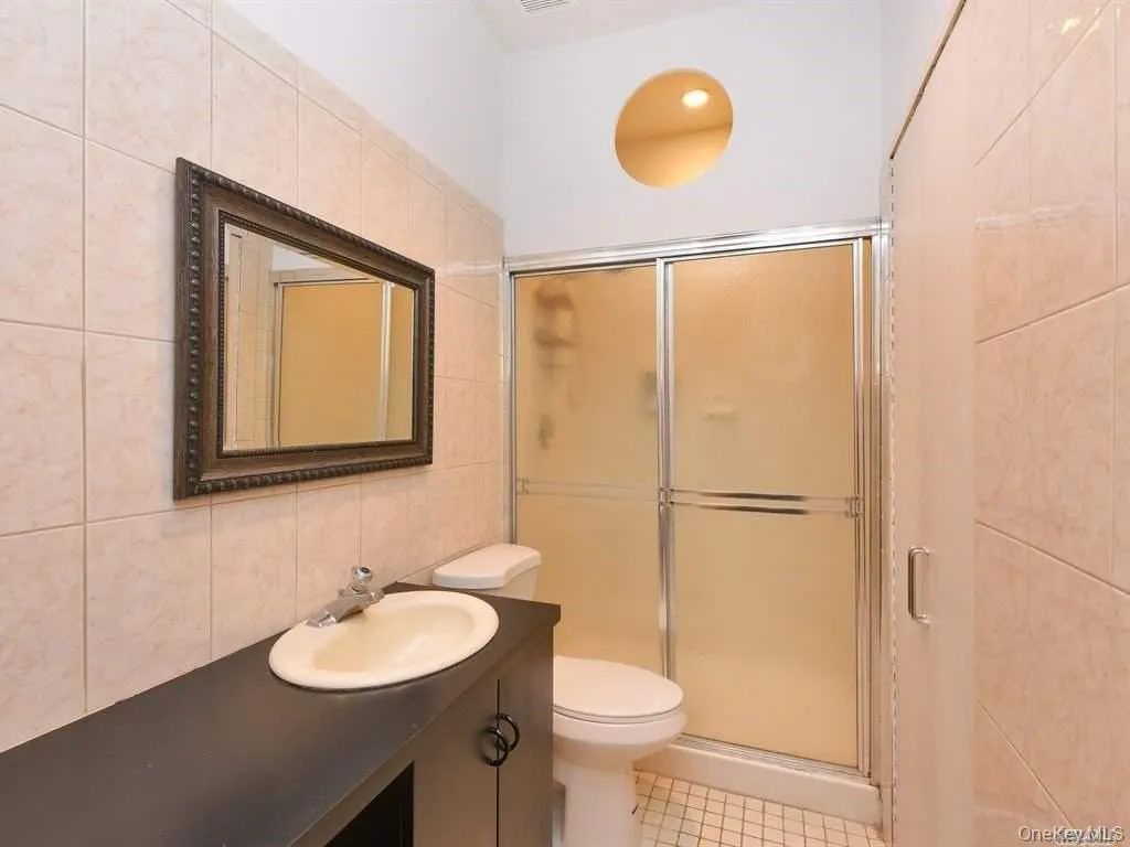 Bathroom featuring tile walls, vanity, a stall shower, and light tile patterned flooring Bathroom featuring tile walls, vanity, a stall shower, and light tile patterned flooring