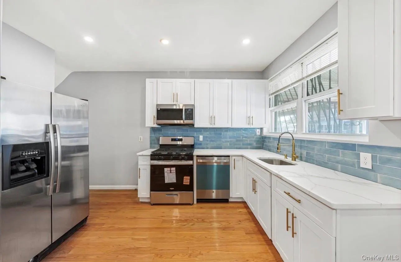 Kitchen with stainless steel appliances, white cabinetry, light stone counters, light wood-style floors, and recessed lighting Kitchen with stainless steel appliances, white cabinetry, light stone counters, light wood-style floors, and recessed lighting