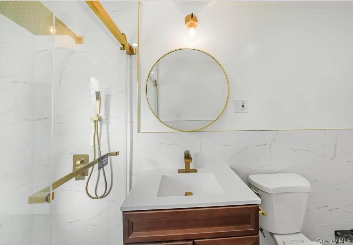 Full bath with tile walls, vanity, a marble finish shower, and wainscoting Full bath with tile walls, vanity, a marble finish shower, and wainscoting