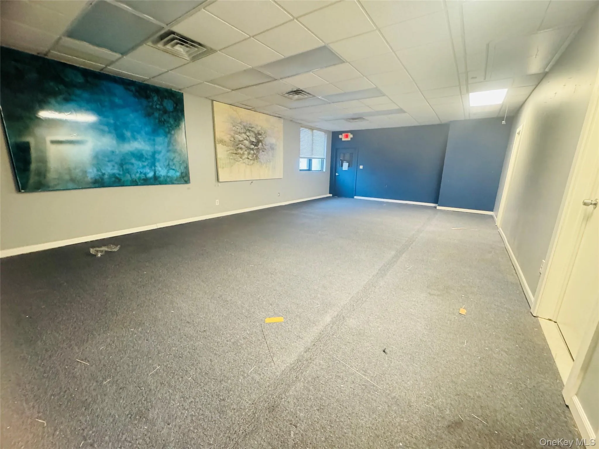 Carpeted spare room with a paneled ceiling and baseboards Carpeted spare room with a paneled ceiling and baseboards