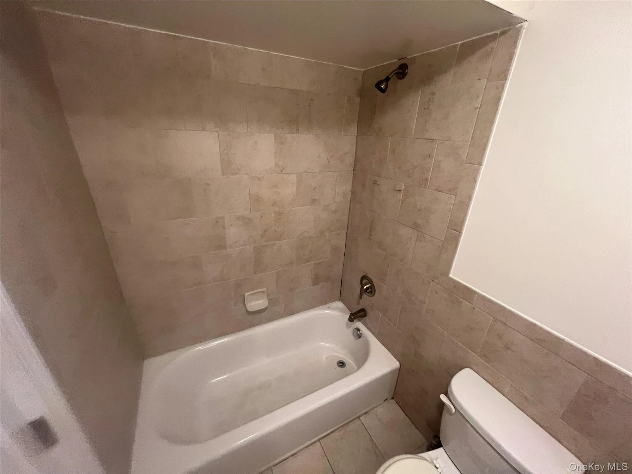 Bathroom featuring shower combination and tile walls Bathroom featuring shower combination and tile walls