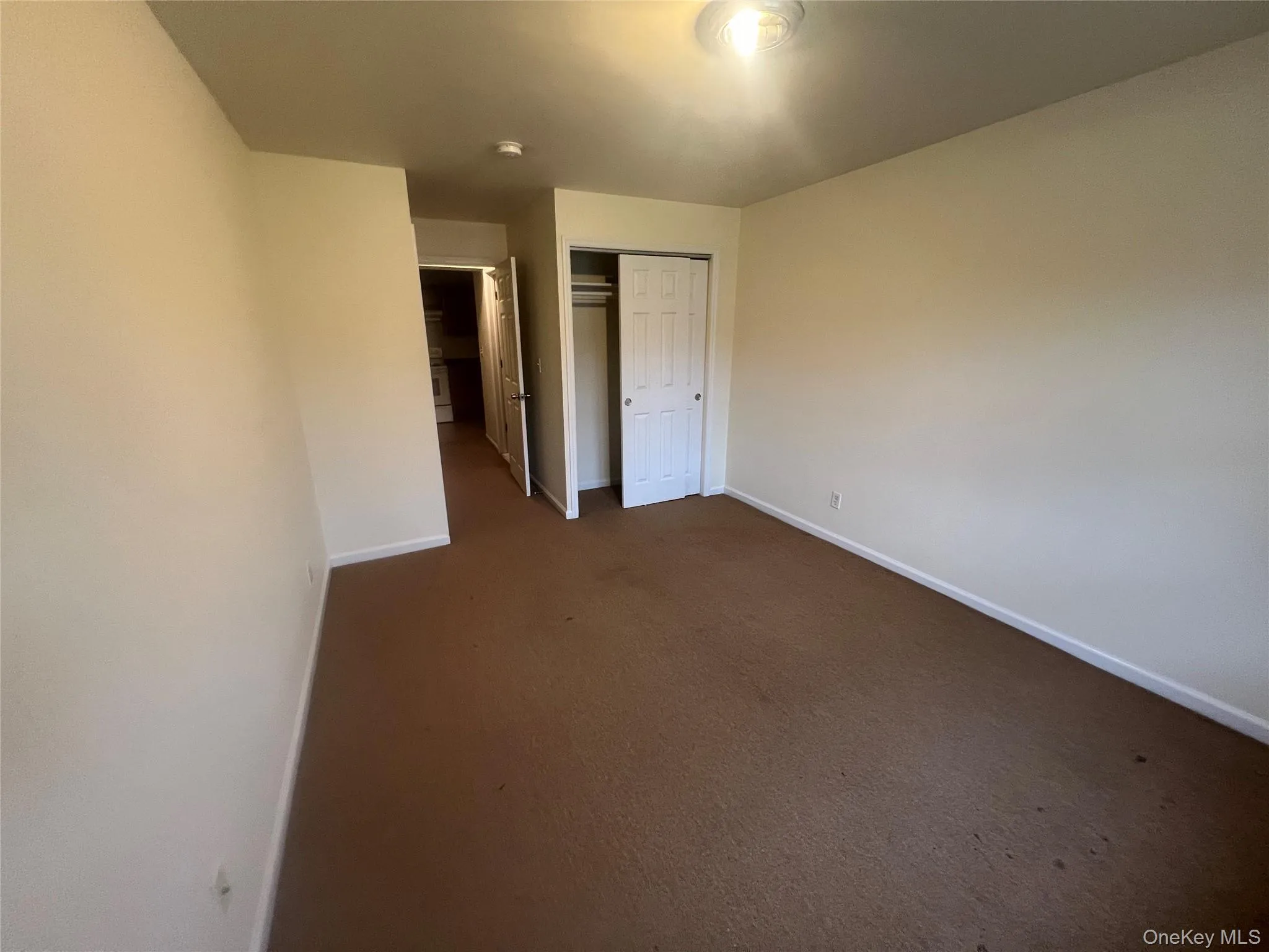 Unfurnished bedroom featuring a closet and dark carpet Unfurnished bedroom featuring a closet and dark carpet