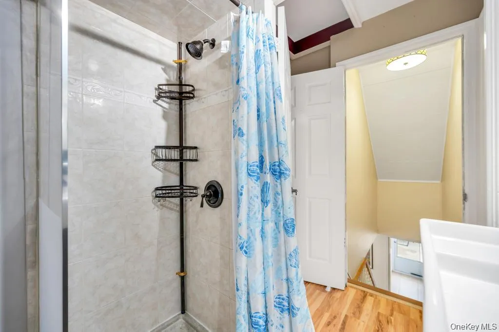 Full bathroom featuring a stall shower and wood finished floors Full bathroom featuring a stall shower and wood finished floors