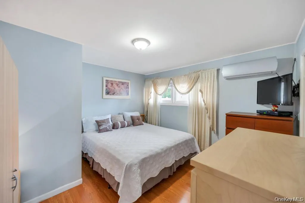 Bedroom with light wood finished floors and a wall mounted air conditioner Bedroom with light wood finished floors and a wall mounted air conditioner