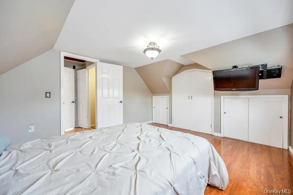 Bedroom with light wood finished floors, vaulted ceiling, and a closet Bedroom with light wood finished floors, vaulted ceiling, and a closet