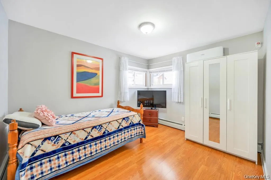 Bedroom featuring baseboard heating and light wood finished floors Bedroom featuring baseboard heating and light wood finished floors