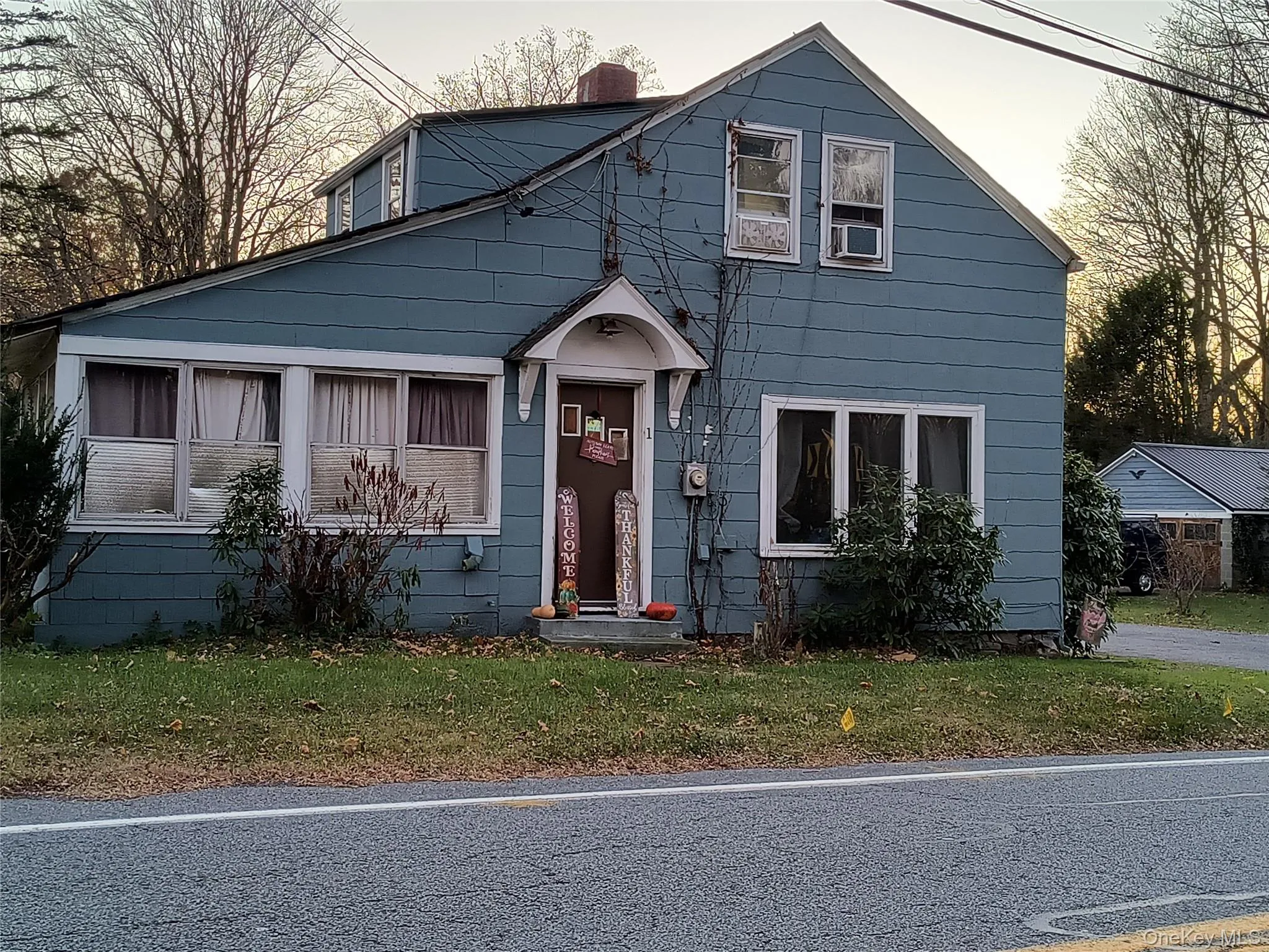 View of front facade featuring a chimney and a front yard View of front facade featuring a chimney and a front yard