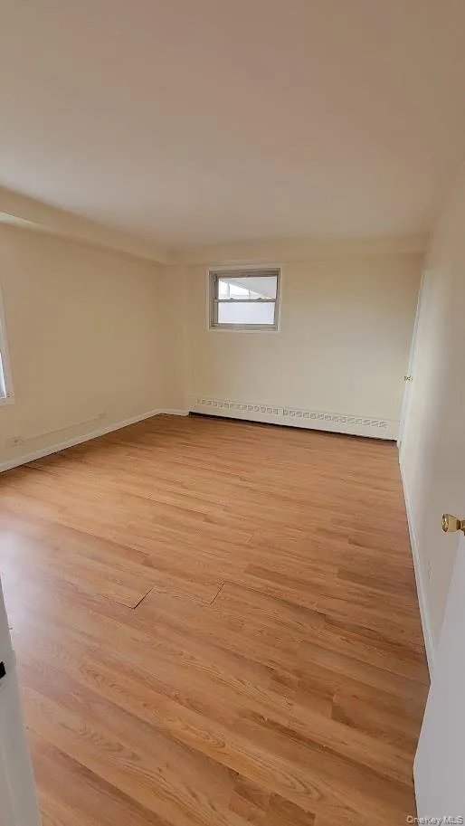 Unfurnished room featuring light wood-type flooring and a baseboard heating unit Unfurnished room featuring light wood-type flooring and a baseboard heating unit