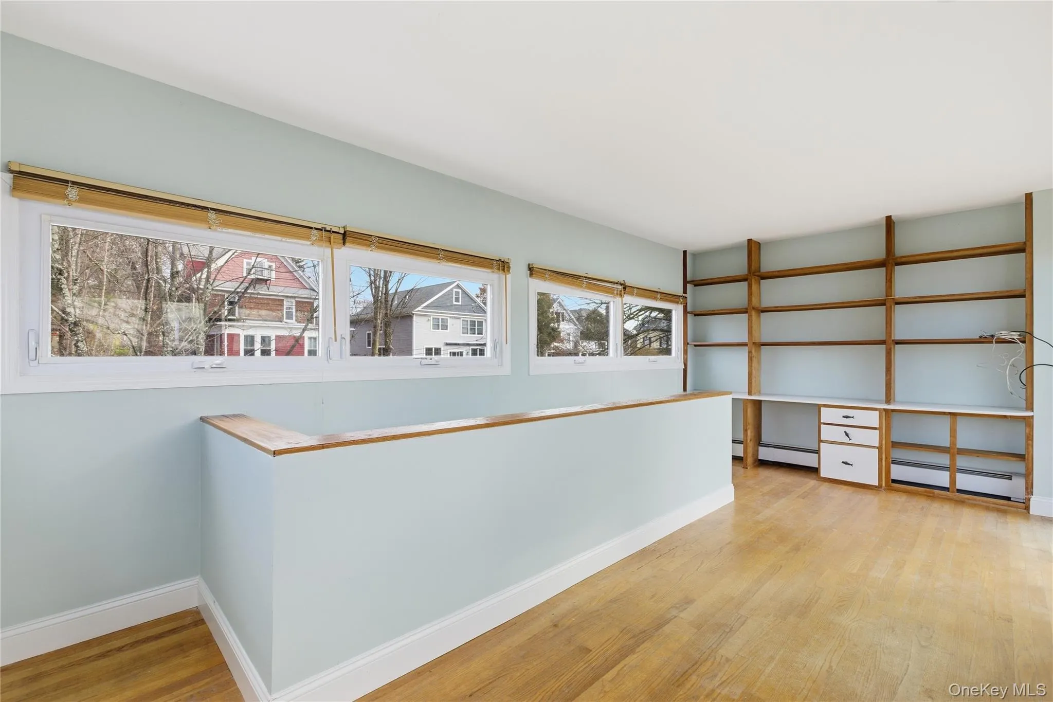 Hallway with light wood-type flooring, an office area, plenty of natural light, and a baseboard heating unit Hallway with light wood-type flooring, an office area, plenty of natural light, and a baseboard heating unit