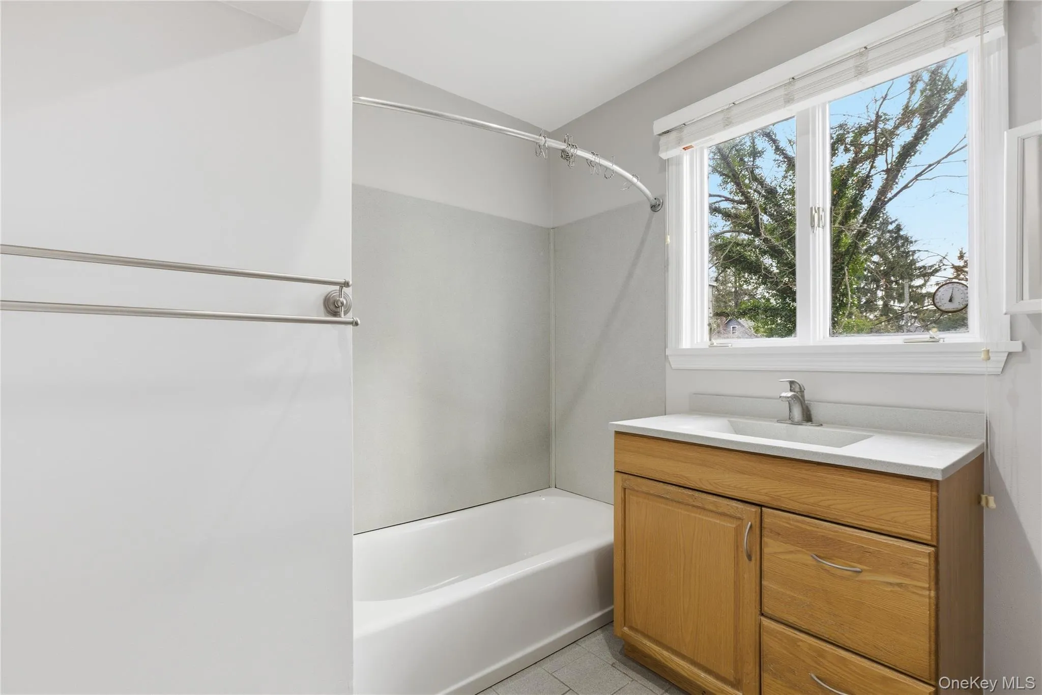 Full bathroom with vanity, shower / bathtub combination, vaulted ceiling, and light tile patterned flooring Full bathroom with vanity, shower / bathtub combination, vaulted ceiling, and light tile patterned flooring