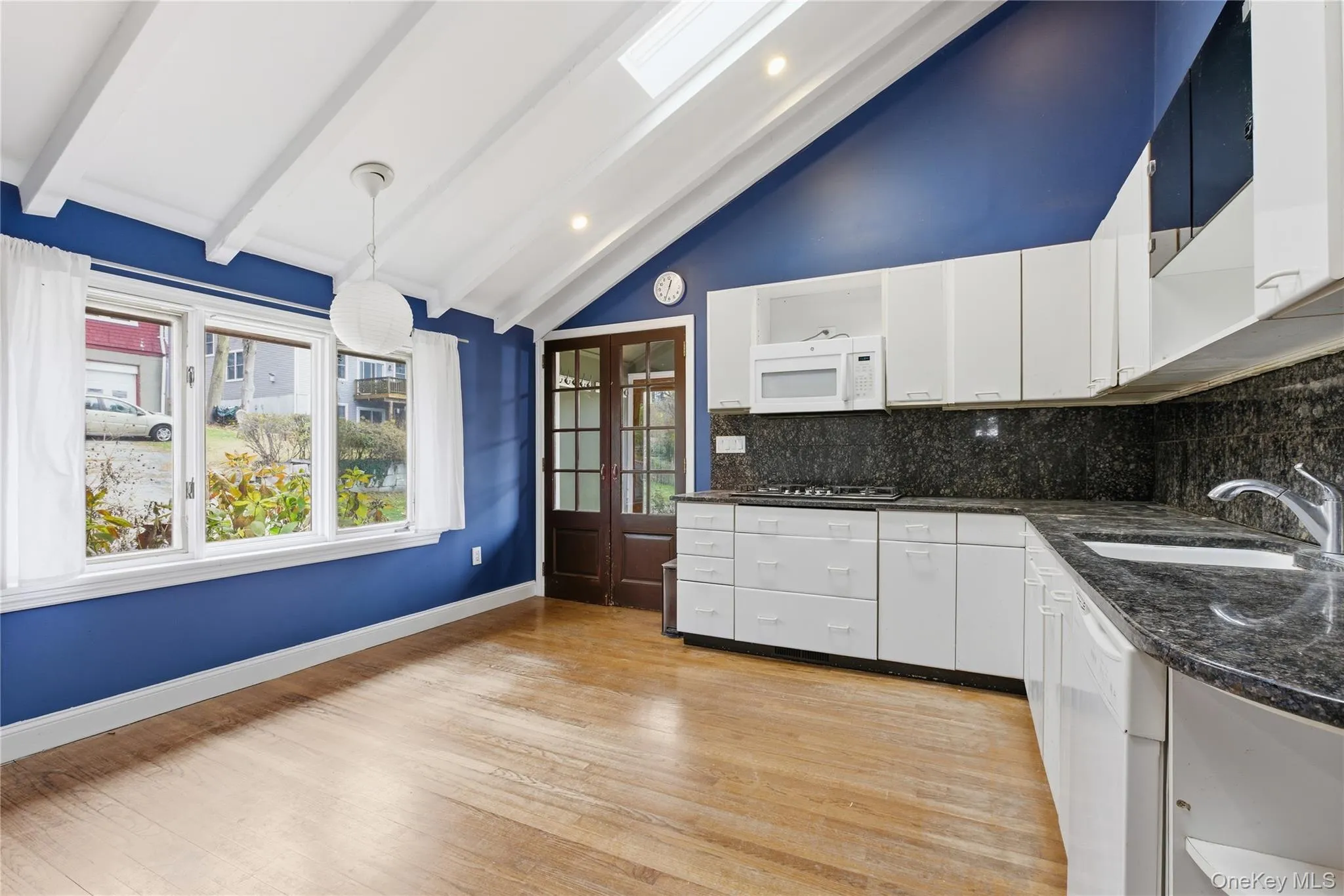 Kitchen featuring open shelves, dark stone countertops, white cabinetry, decorative light fixtures, and beam ceiling Kitchen featuring open shelves, dark stone countertops, white cabinetry, decorative light fixtures, and beam ceiling