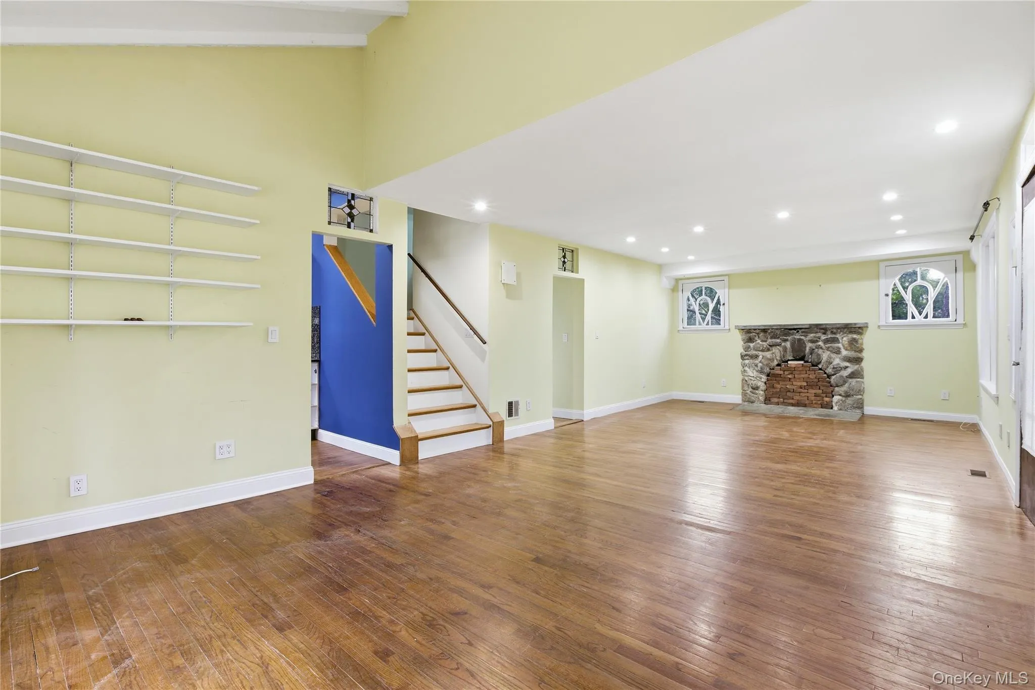 Unfurnished living room with dark wood-type flooring, stairs, recessed lighting, and a fireplace Unfurnished living room with dark wood-type flooring, stairs, recessed lighting, and a fireplace