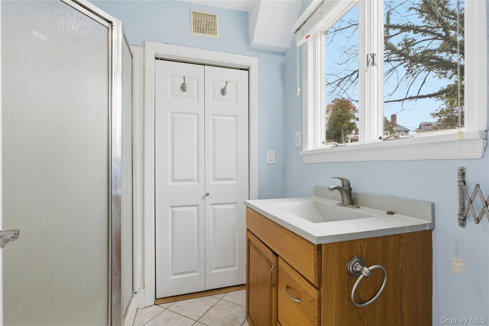 Bathroom with vanity, a stall shower, light tile patterned floors, and a closet Bathroom with vanity, a stall shower, light tile patterned floors, and a closet