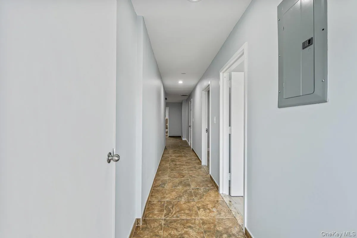 Corridor featuring electric panel, recessed lighting, and stone finish flooring Corridor featuring electric panel, recessed lighting, and stone finish flooring