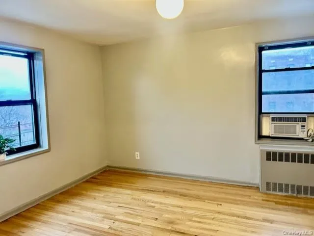 Another view of bedroom room radiator heating unit, light wood-style floors, and cooling unit Another view of bedroom room radiator heating unit, light wood-style floors, and cooling unit