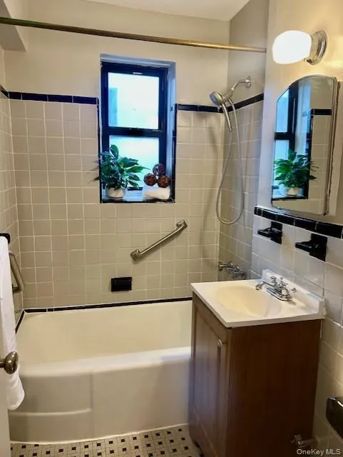 Full bathroom with shower / bathtub combination, vanity, and tile walls Full bathroom with shower / bathtub combination, vanity, and tile walls