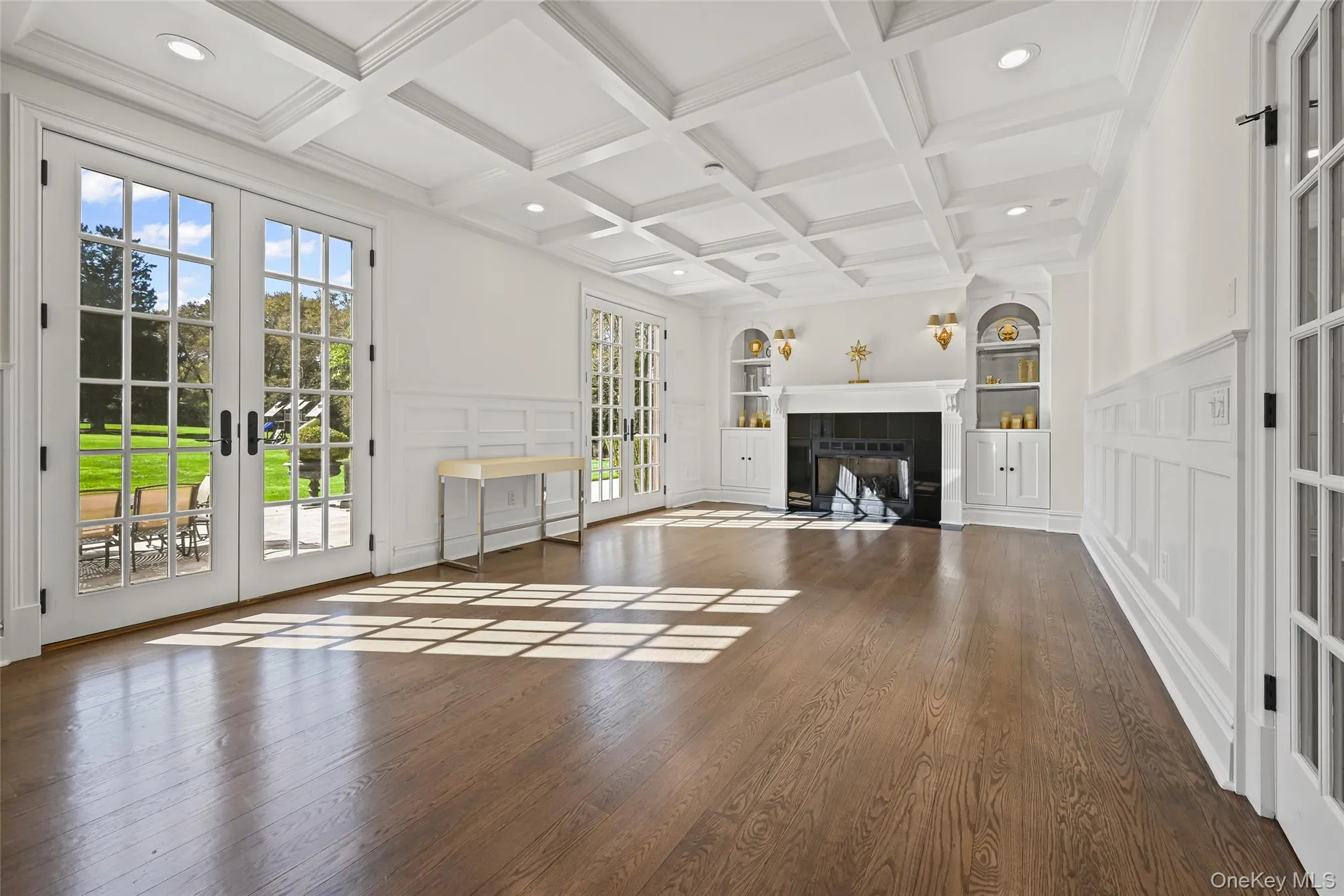 Unfurnished living room featuring french doors, a decorative wall, built in features, hardwood / wood-style flooring, and coffered ceiling Unfurnished living room featuring french doors, a decorative wall, built in features, hardwood / wood-style flooring, and coffered ceiling