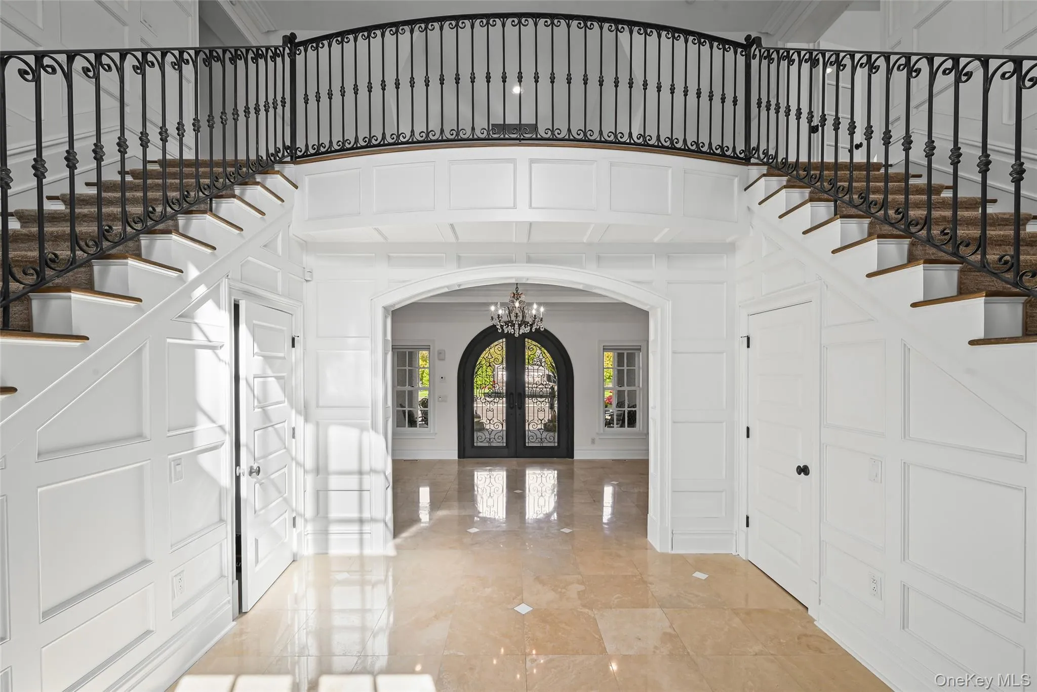 Foyer featuring stairway, a decorative wall, arched walkways, a chandelier, and french doors Foyer featuring stairway, a decorative wall, arched walkways, a chandelier, and french doors