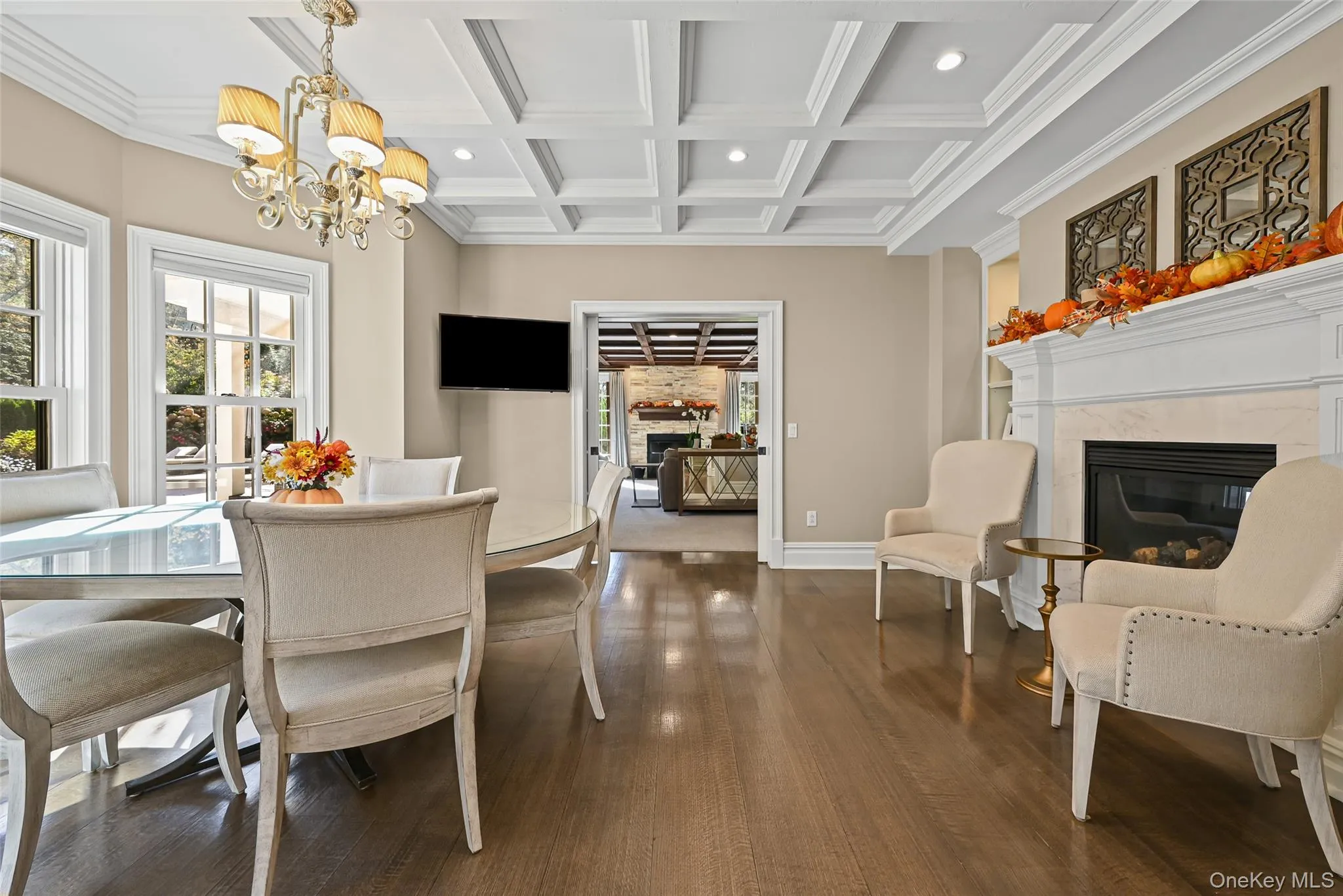 Dining space featuring a high end fireplace, coffered ceiling, beamed ceiling, dark wood finished floors, and crown molding Dining space featuring a high end fireplace, coffered ceiling, beamed ceiling, dark wood finished floors, and crown molding