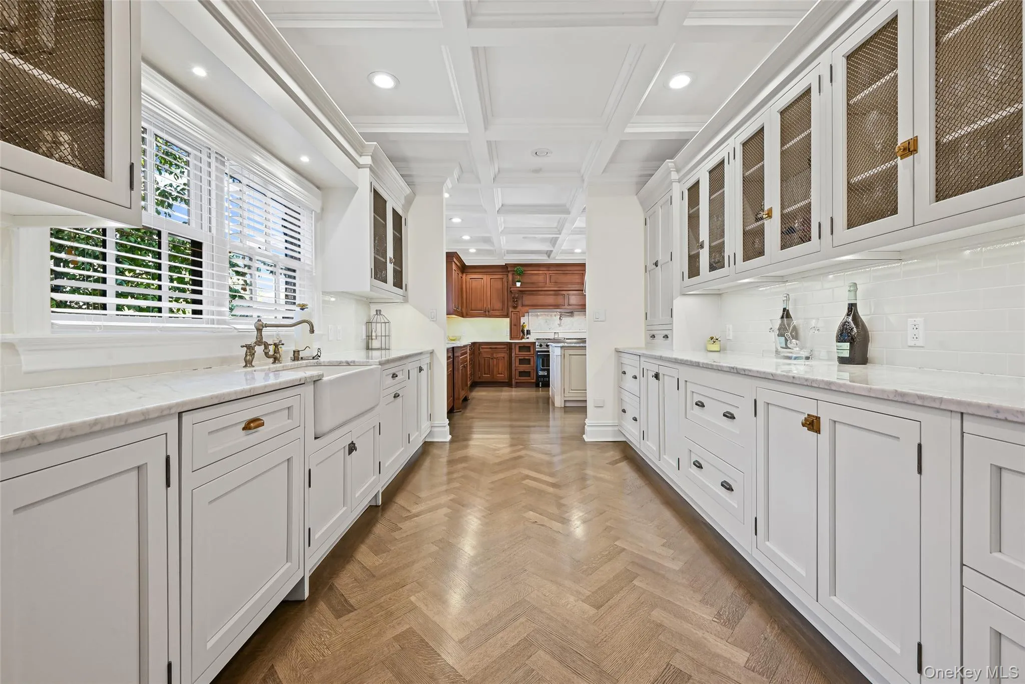 Bar area with white cabinetry, glass insert cabinets, backsplash, coffered ceiling, and light stone counters Bar area with white cabinetry, glass insert cabinets, backsplash, coffered ceiling, and light stone counters