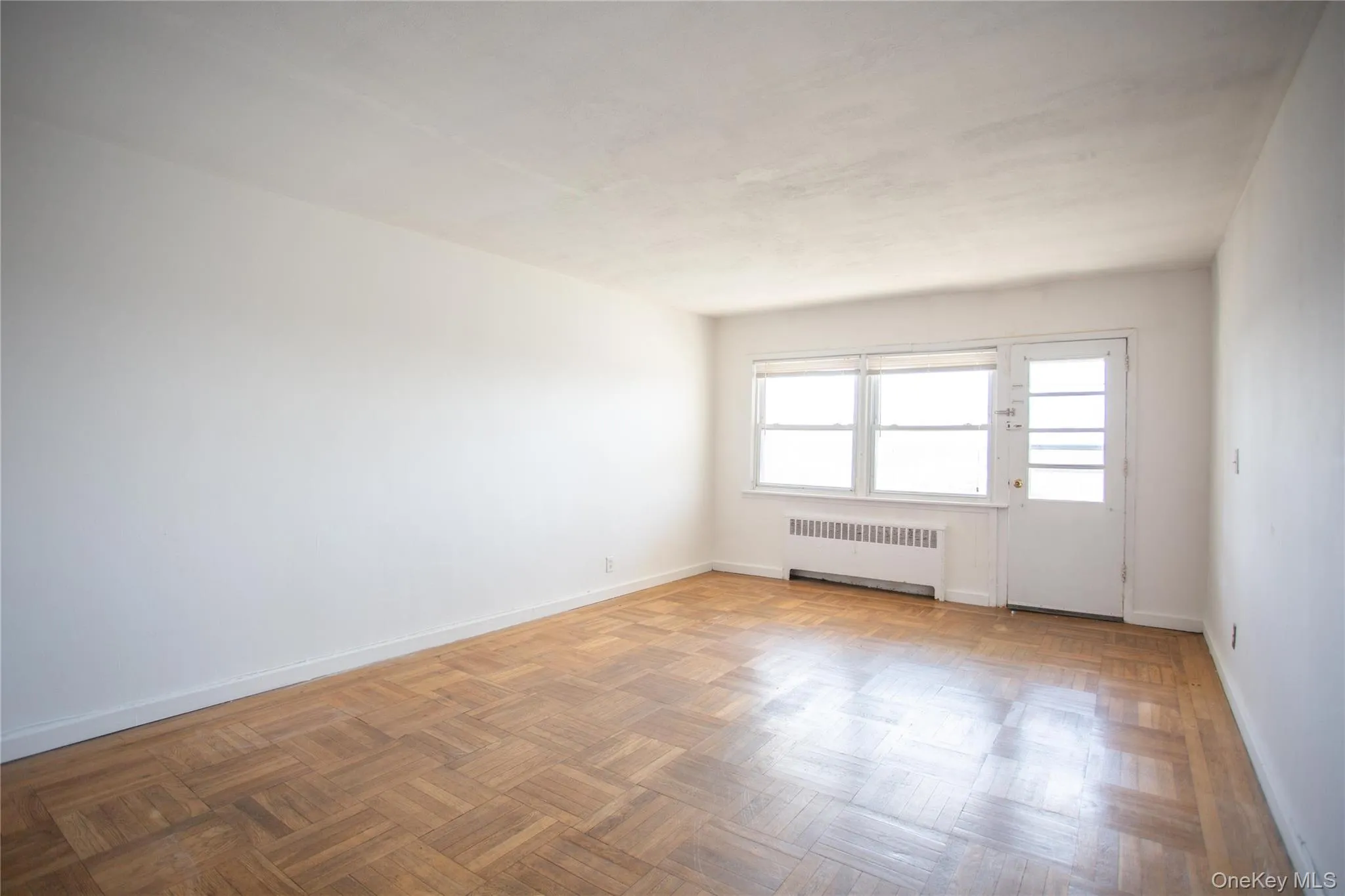 Empty room featuring radiator heating unit and baseboards Empty room featuring radiator heating unit and baseboards