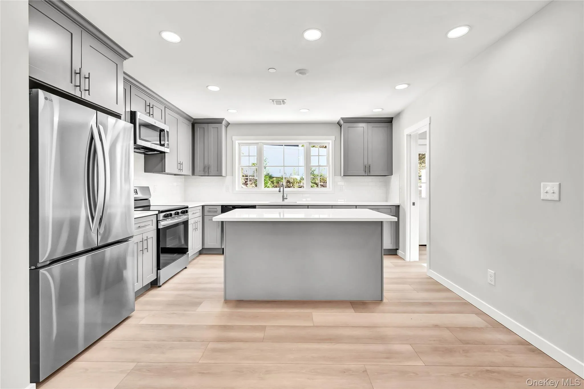 Kitchen with stainless steel appliances, a kitchen island, gray cabinetry, tasteful backsplash, and recessed lighting Kitchen with stainless steel appliances, a kitchen island, gray cabinetry, tasteful backsplash, and recessed lighting