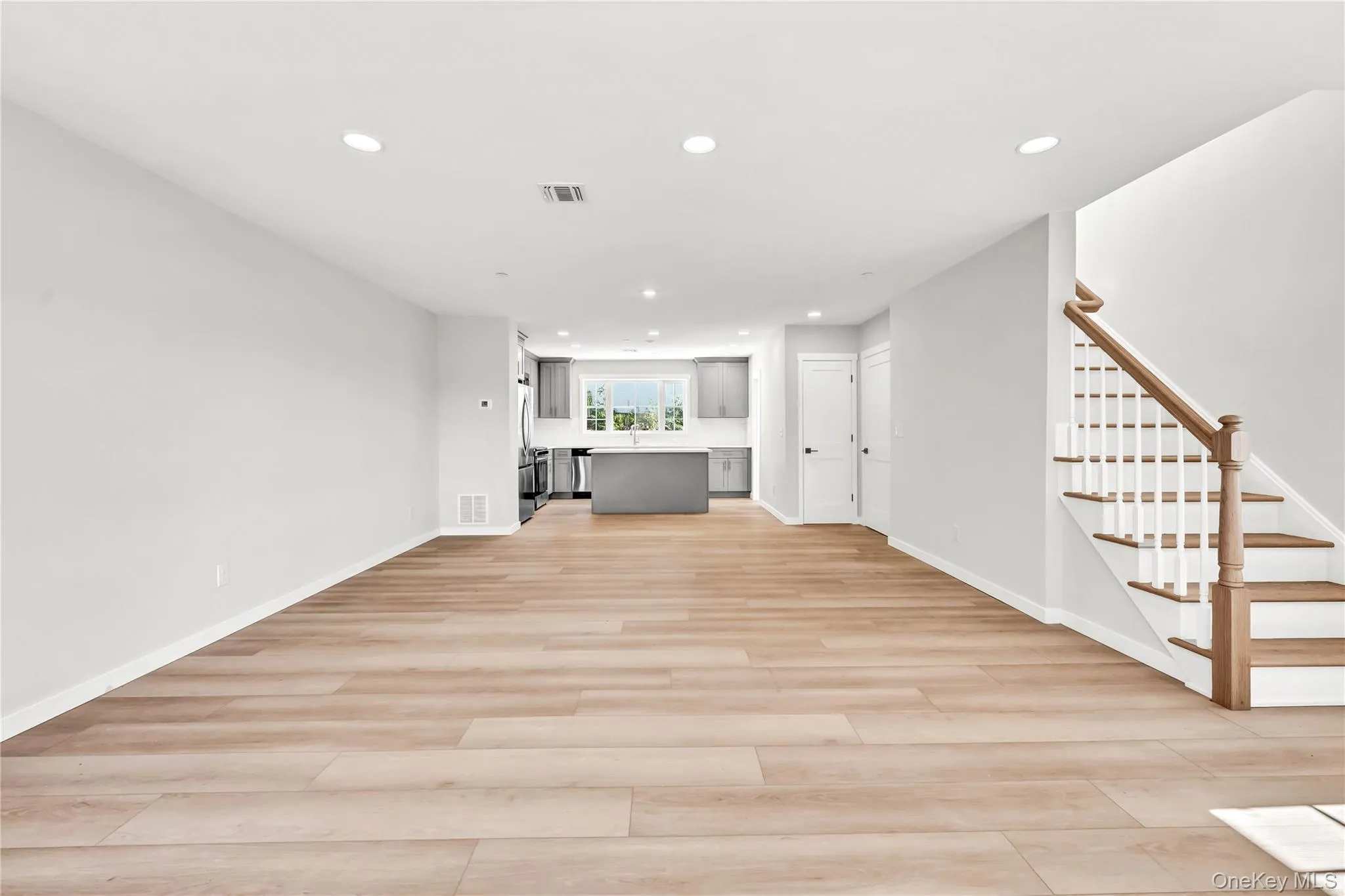 Unfurnished living room featuring stairs, recessed lighting, and light wood-style floors Unfurnished living room featuring stairs, recessed lighting, and light wood-style floors