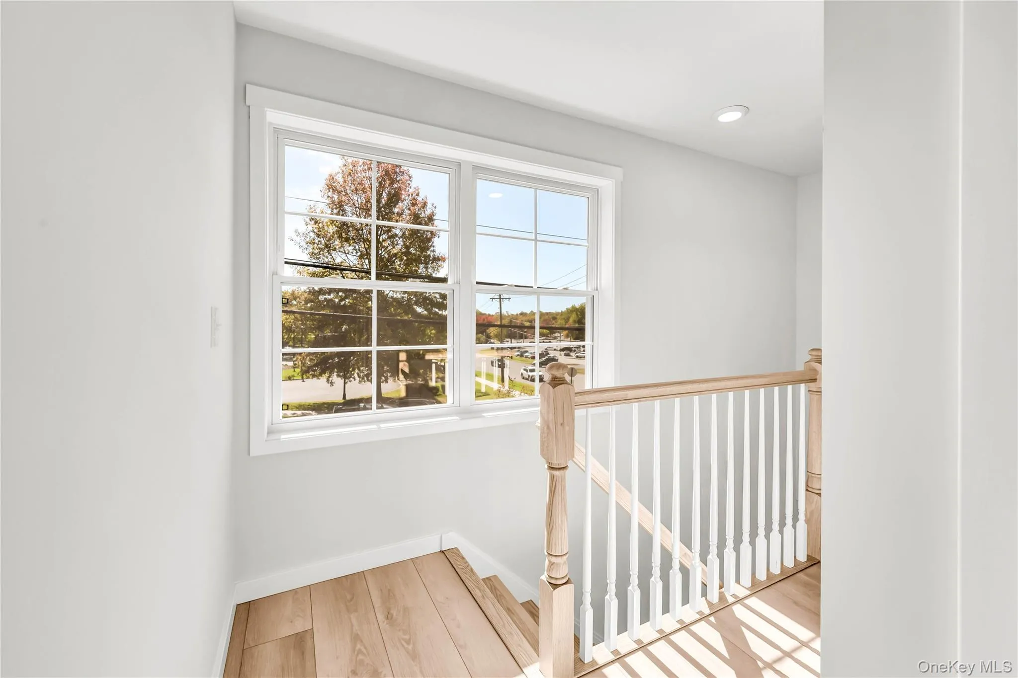 Hallway with an upstairs landing, light wood finished floors, and recessed lighting Hallway with an upstairs landing, light wood finished floors, and recessed lighting